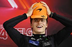 a young man wearing an orange hat and black shirt with his hands on his head