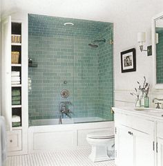 a bathroom with green tile and white fixtures, including a shower stall in the corner