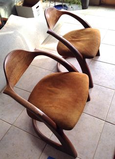 three wooden chairs sitting on top of a tiled floor