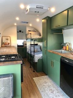 a kitchen with green cabinets and an oven in the center is next to a bed