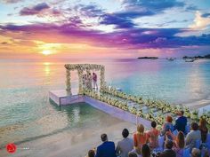 an outdoor ceremony on the beach at sunset