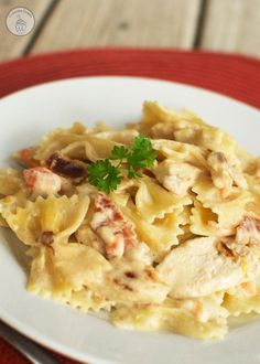 a white plate topped with pasta covered in chicken and cheese sauce, garnished with parsley