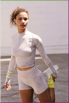 a woman in tight white clothing walking down the street with her hand on her hip