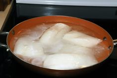 some fish are being cooked in a pan on the stove top with water and ice