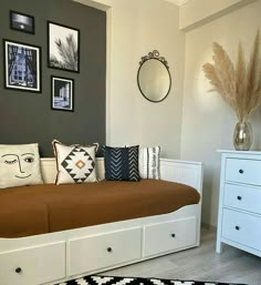 a white daybed with lots of pillows and pictures on the wall