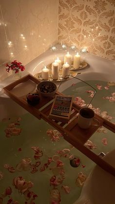 a bathtub with candles and flowers on the floor next to it in a bathroom