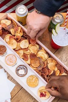 two people grabbing food from a tray on a table