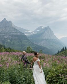 a bride and groom walk through the wildflowers on their wedding day in the mountains