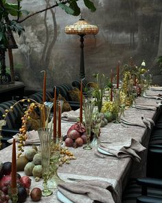 a long table is set with candles, fruit and other items for an elegant dinner