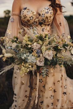 a woman in a wedding dress holding a bouquet with flowers and feathers on her chest