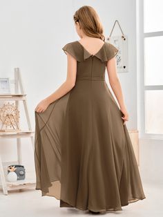 a woman in a brown dress is looking back at the camera and she has her hands on her hips