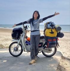 a woman standing next to a motorcycle with her arms outstretched in front of the camera