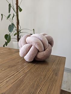 a pink knot sitting on top of a wooden table next to a potted plant