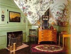 the room is decorated in green and has floral wallpaper on the walls, along with an antique chest of drawers