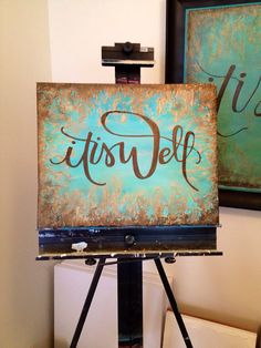 an easel with a sign that says it's self in front of two paintings