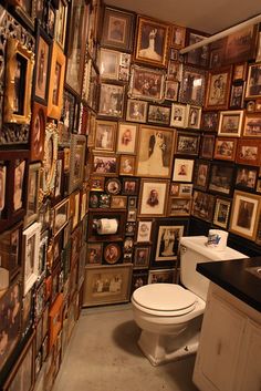 a toilet and sink in a small room with many pictures on the wall