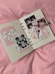 an open book with pictures and stickers on it sitting on a pink bed sheet