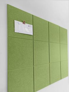 a green bulletin board with notes pinned to it's sides on a white wall