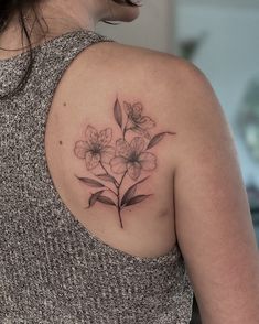 a woman with a tattoo on her shoulder has flowers in the middle of her arm