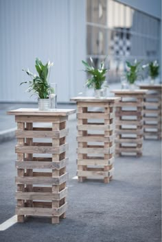 three vases with flowers in them are lined up on wooden pallets outside the building