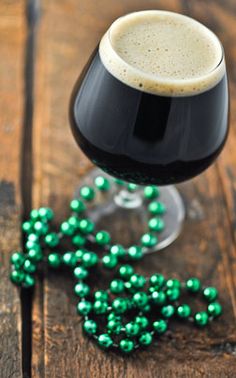 a close up of a wine glass on a wooden table with green beads around it