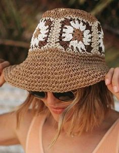 a woman wearing a brown and white crochet hat with sun glasses on her head