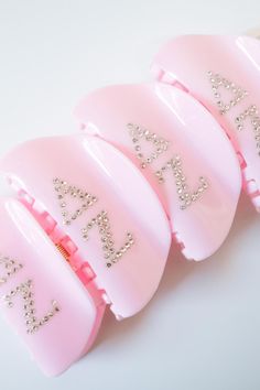 three pink combs with glitter on them sitting next to each other in front of a white background