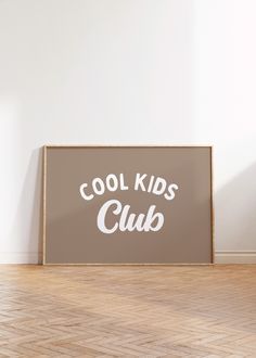 a sign that says cool kids club in white on a wood floor next to a wall