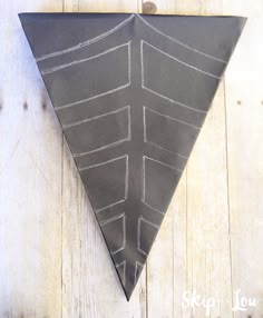 a black triangle with white lines on it sitting on top of a wooden floor next to a wall