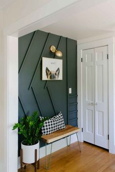 a room with a bench, potted plant and pictures on the wall