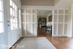 an open door leading to a dining room and living room with white walls, wood flooring and hardwood floors