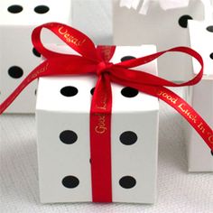 three white boxes with black polka dots and a red ribbon tied around the top one