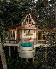 an outdoor hot tub in the middle of trees with a person laying on top of it