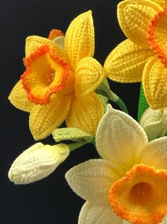 crocheted daffodils are displayed on a black surface with a woman's face in the background