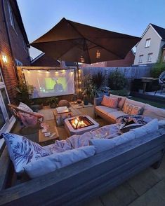 an outdoor living area with couches, tables and umbrellas in the evening time