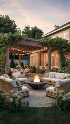 a fire pit in the middle of a patio with wicker furniture and string lights