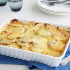 a casserole dish on a blue napkin with silverware and plates in the background