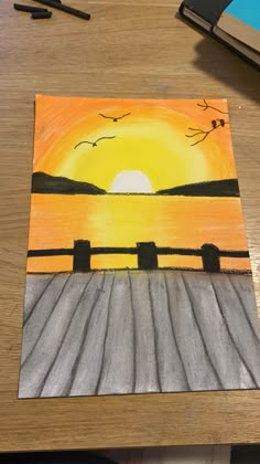 a drawing of a sunset on a wooden table