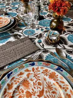 the table is set with plates, silverware and flowers in vases on it