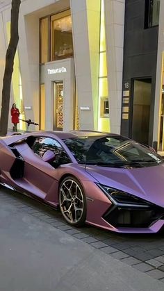 a purple sports car parked on the side of a street next to a tall building