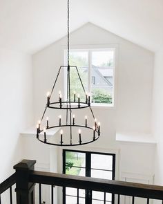 a chandelier hanging from the ceiling in a room with white walls and windows