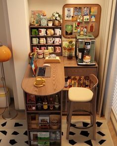 a small desk with a laptop on top of it next to a shelf full of coffee cups