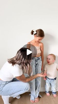 a woman and two children standing in front of a wall