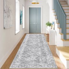 a large rug is in the middle of a room with stairs and blue painted doors