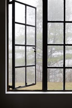 an open window with the view of a field through it and trees in the background