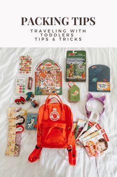 an orange backpack sitting on top of a white bed next to other items and accessories