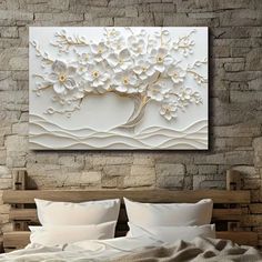 a bed with white sheets and pillows in front of a wall mounted painting on it