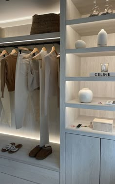 an open closet with clothes and shoes on shelves