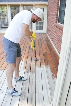 a man is using a drill to fix a wooden deck with a yellow hose attached