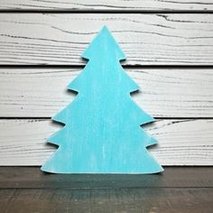 a small wooden christmas tree sitting on top of a table next to a white wall